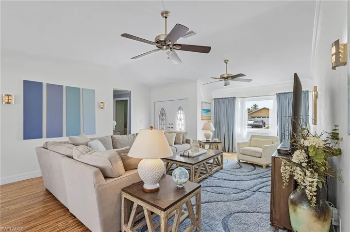 Living room featuring lofted ceiling, french doors, crown molding, ceiling fan, and light wood-type flooring