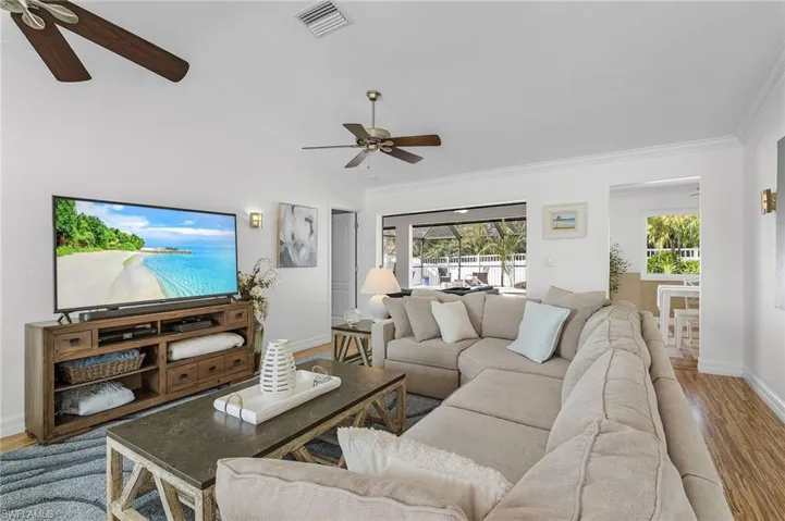 Living room with hardwood / wood-style flooring, ceiling fan, and crown molding