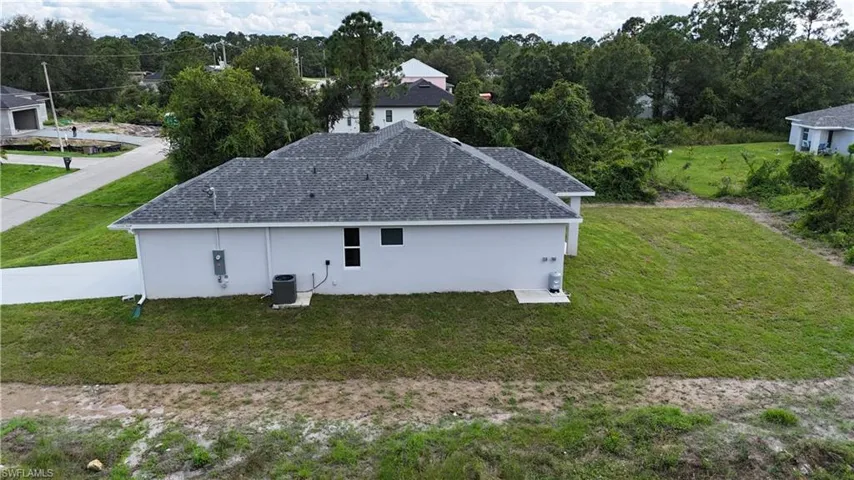 View of property exterior with a lawn, stucco siding, and a shingled roof