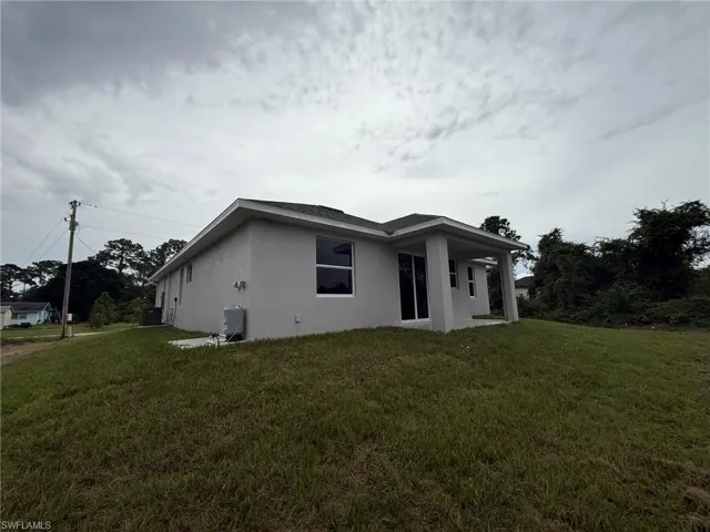 Back of property with stucco siding, a lawn, and a patio area