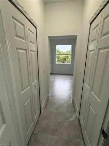 Hall featuring a textured wall and baseboards