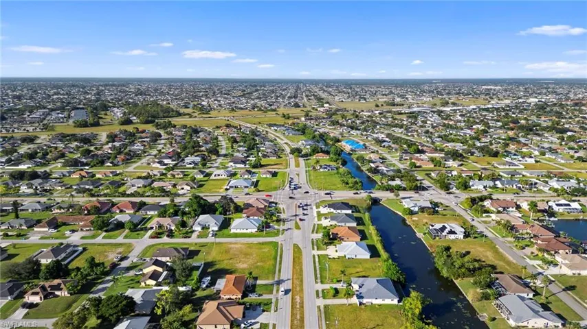 Aerial view of property and surrounding area featuring nearby suburban area and a nearby body of water