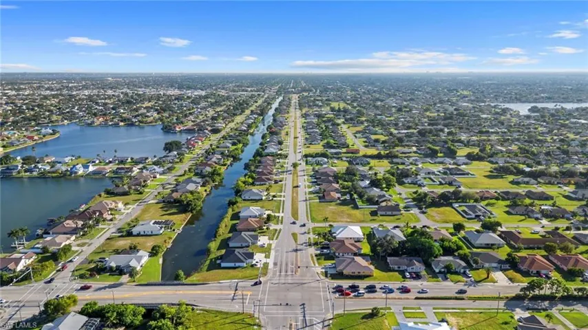 Aerial view of property and surrounding area featuring a nearby body of water and nearby suburban area