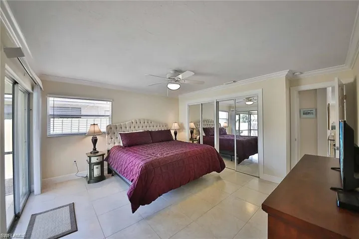 Bedroom featuring light tile patterned floors, baseboards, ceiling fan, and crown molding