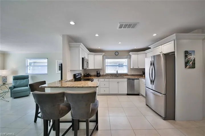 Kitchen with visible vents, light stone counters, appliances with stainless steel finishes, a peninsula, and a sink