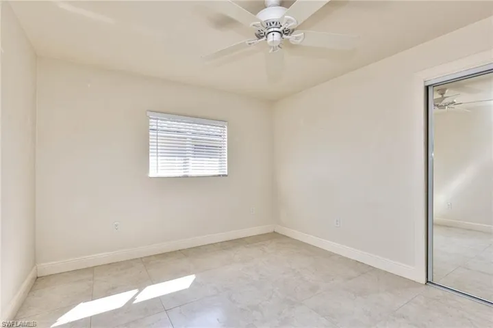 Tiled spare room featuring a ceiling fan and baseboards