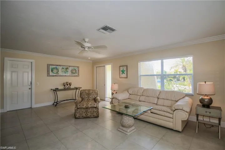 Tiled living room featuring visible vents, crown molding, and baseboards