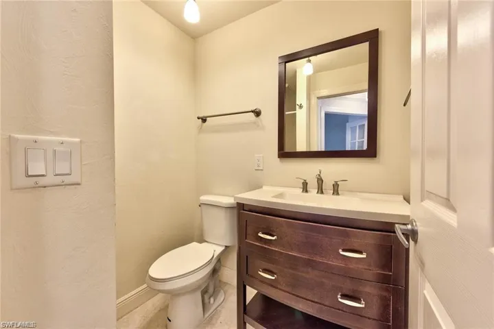 Half bathroom featuring tile patterned floors, toilet, vanity, and baseboards