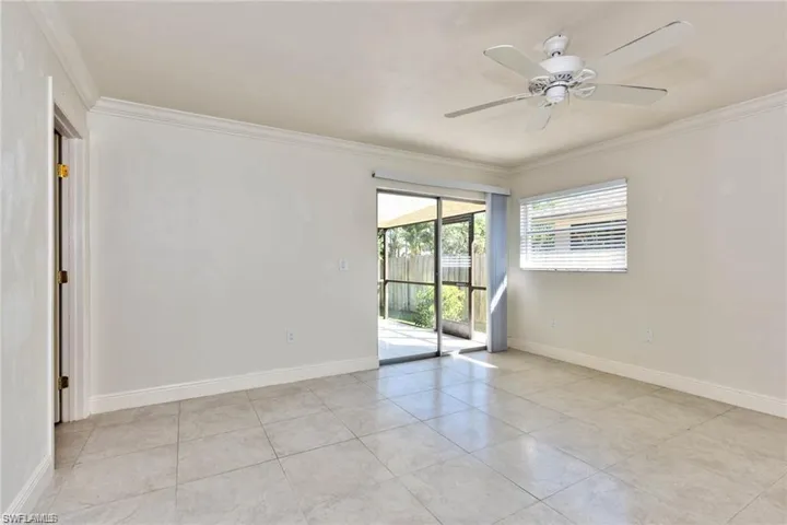 Unfurnished room featuring light tile patterned floors, a ceiling fan, baseboards, and ornamental molding