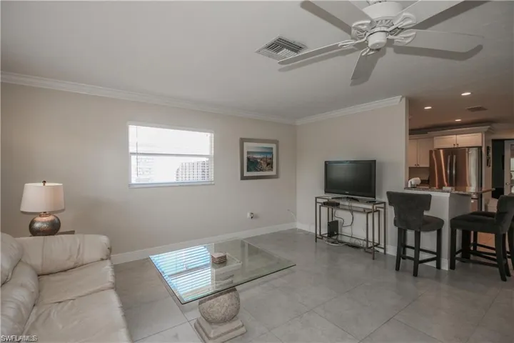 Living area featuring visible vents, baseboards, and crown molding