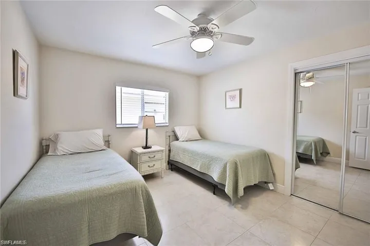Bedroom featuring light tile patterned floors, a closet, baseboards, and a ceiling fan
