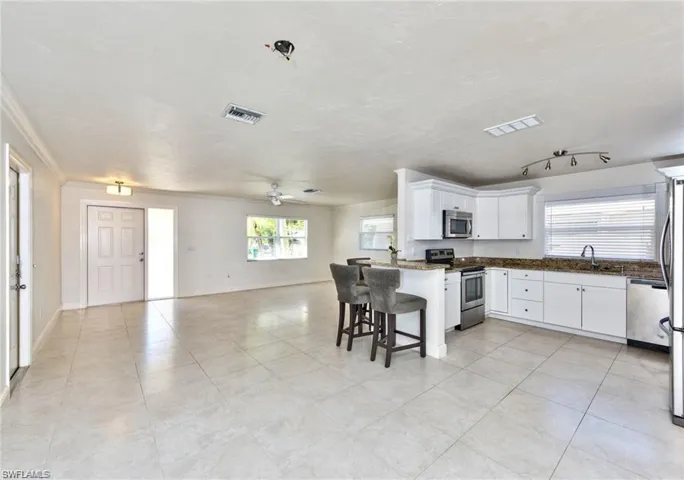 Kitchen featuring visible vents, a sink, white cabinets, appliances with stainless steel finishes, and open floor plan