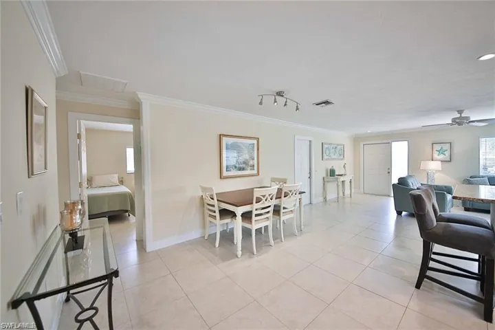 Dining area with light tile patterned flooring, baseboards, visible vents, and ornamental molding