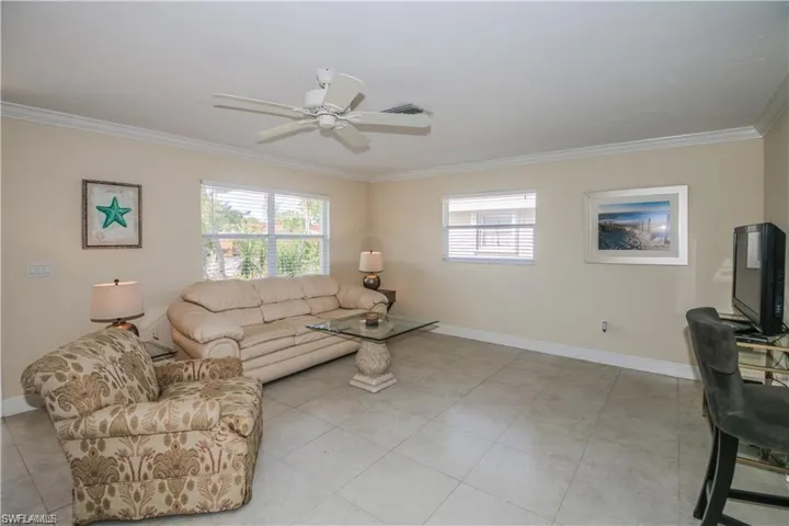 Living room featuring crown molding, a ceiling fan, baseboards, and visible vents