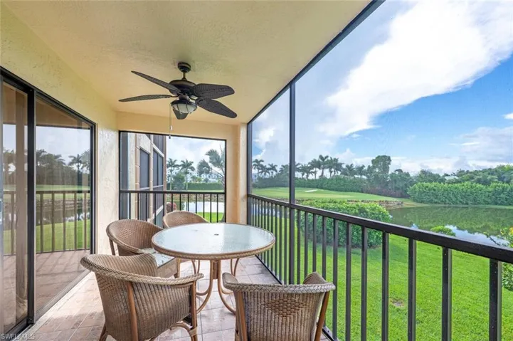 Sunroom / solarium with a balcony, a water view, ceiling fan, and view of wooded area