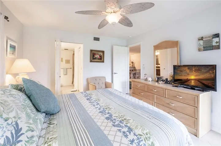 Bedroom featuring light tile patterned floors, connected bathroom, and ceiling fan