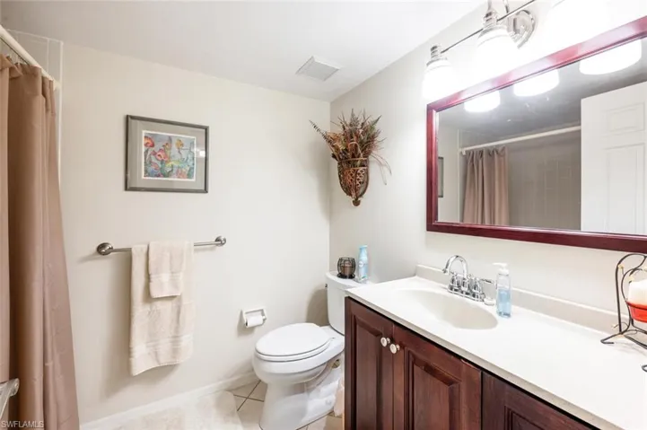 Full bath featuring light tile patterned floors, vanity, and curtained shower