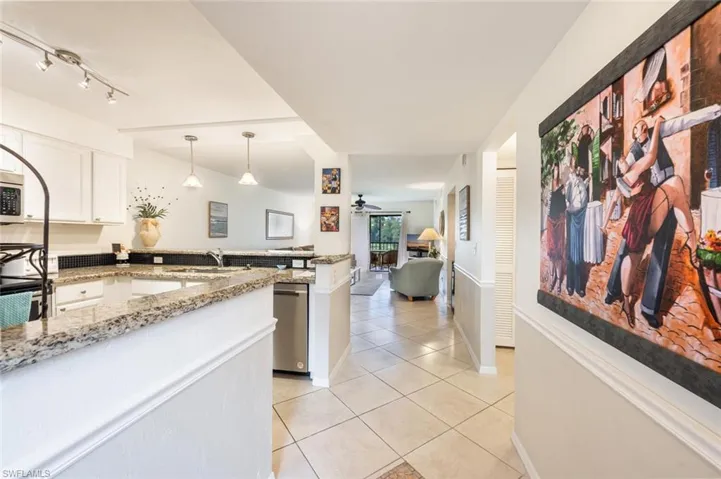 Kitchen with pendant lighting, white cabinets, light tile patterned flooring, light stone counters, and appliances with stainless steel finishes