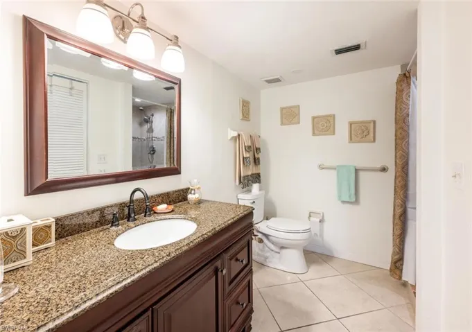 Full bathroom featuring vanity, light tile patterned flooring, and a shower with curtain