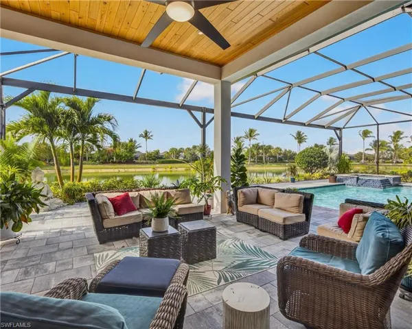 View of patio / terrace featuring a lanai, a hot tub, a sunroom, and a water view
