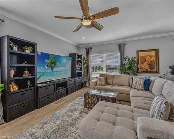 Bedroom with ornamental molding, wood finished floors, and a ceiling fan