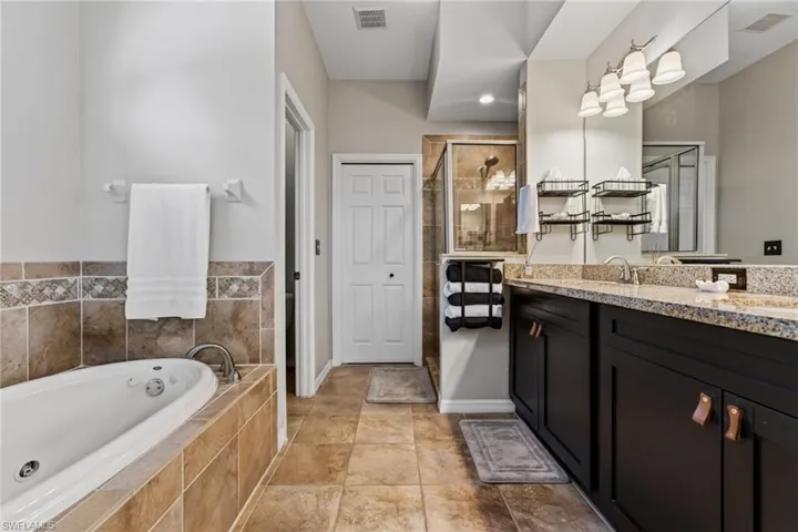 Bathroom with double vanity, a stall shower, and a garden tub