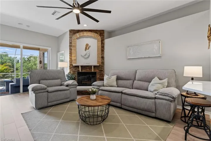 Living room with ceiling fan, a stone fireplace, light wood-style floors, and recessed lighting
