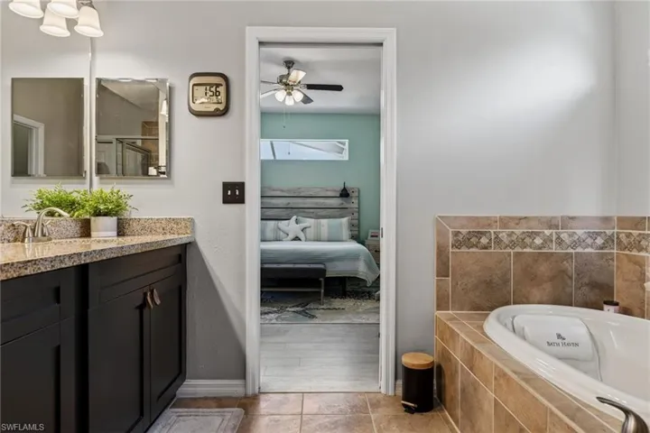 Bathroom featuring vanity, ensuite bath, a ceiling fan, a garden tub, and light tile patterned floors