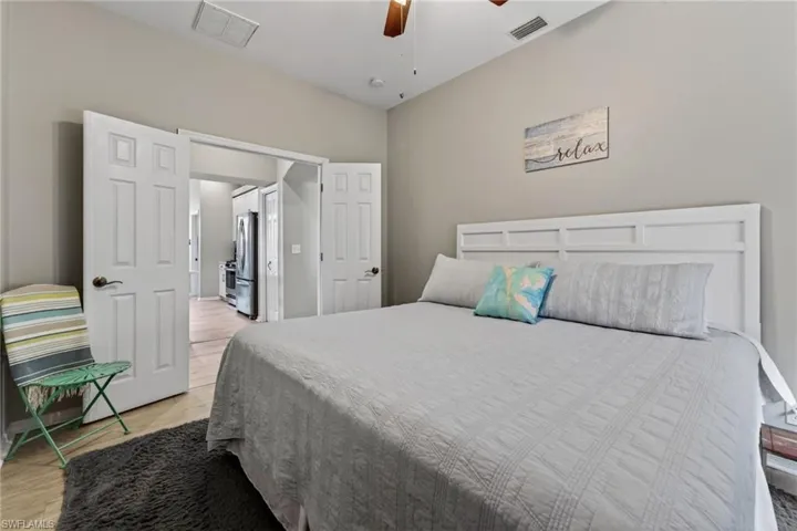 Bedroom featuring ceiling fan, freestanding refrigerator, and light wood-style floors