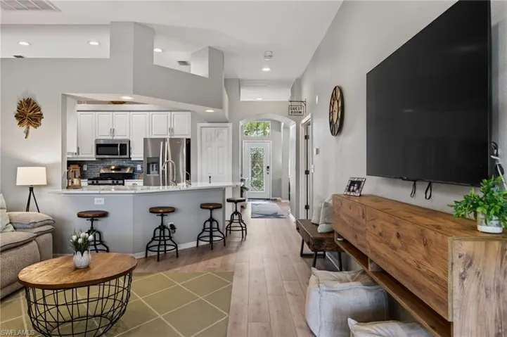 Living area with arched walkways, light wood finished floors, and recessed lighting