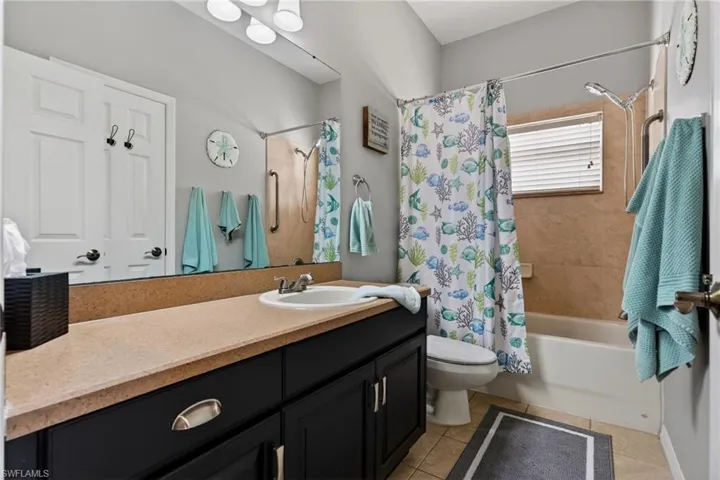 Bathroom with vanity, shower / bath combination with curtain, and light tile patterned flooring