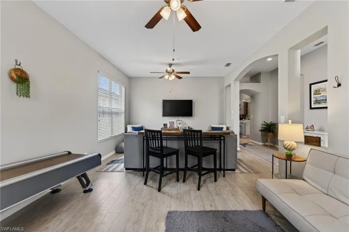 Living room with a ceiling fan, light wood-type flooring, and arched walkways