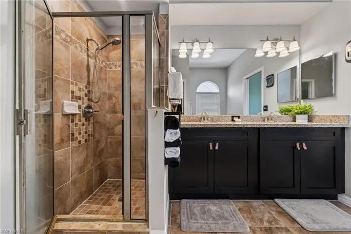 Full bathroom with double vanity and a stall shower