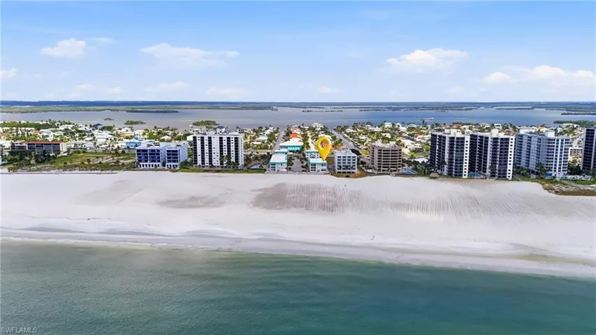 Aerial perspective featuring direct oceanfront positioning, expansive sandy shoreline, and proximity to coastal waters