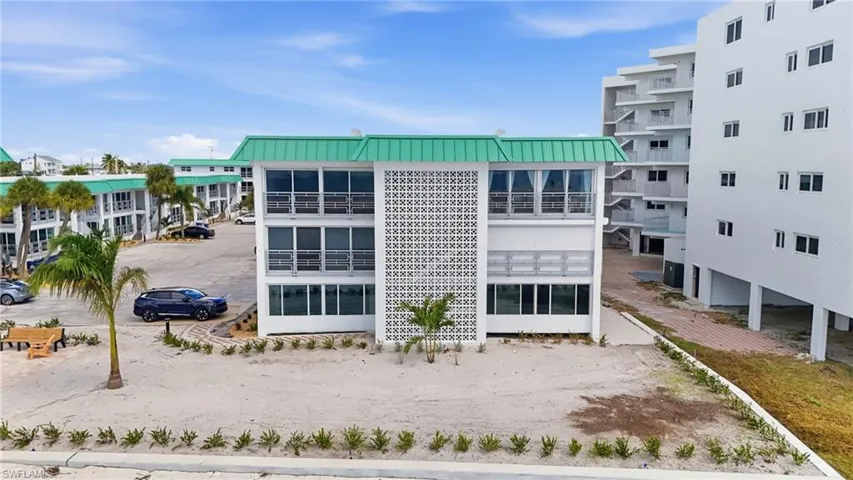 Multi-story exterior featuring white stucco siding, a decorative breeze block facade, metal roof accents, and floor-to-ceiling windows