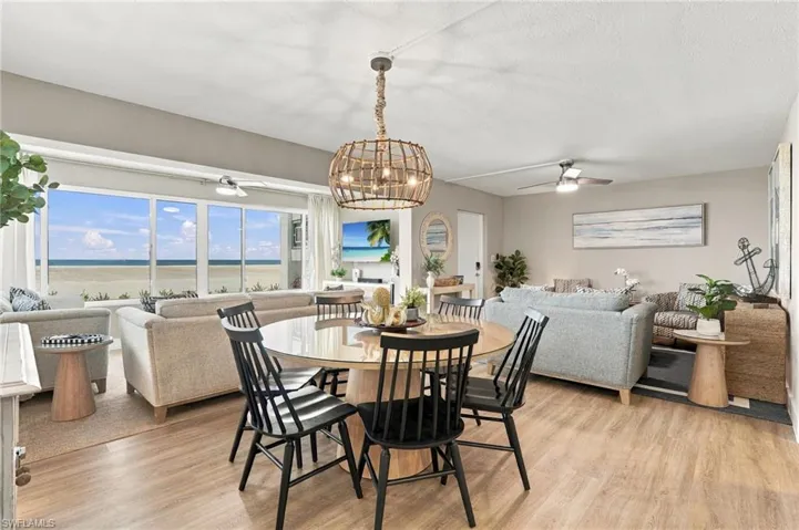 Open-concept living space featuring wood-finish flooring, floor-to-ceiling windows, and a woven pendant light fixture