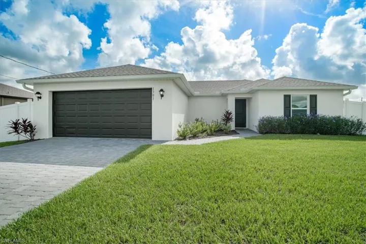 Ranch-style home featuring a garage and a front lawn