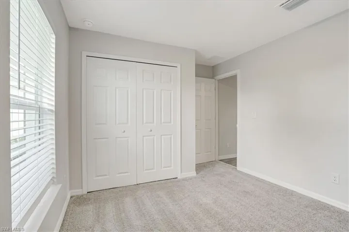 Unfurnished bedroom featuring light carpet and a closet