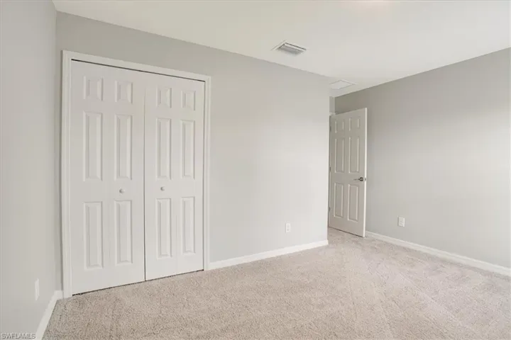 Unfurnished bedroom featuring light carpet and a closet