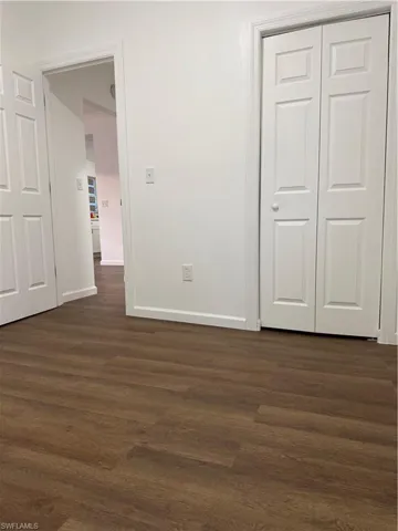 Unfurnished bedroom with dark wood-style floors and a closet