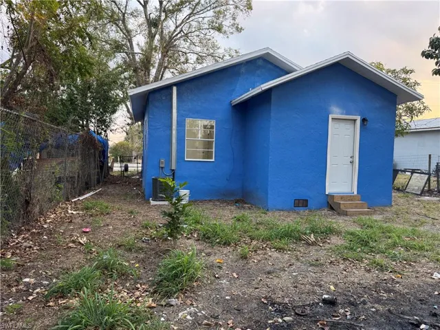 Back of property with stucco siding, crawl space, and entry steps