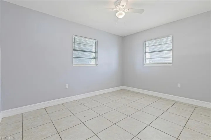 Unfurnished room with ceiling fan and light tile floors