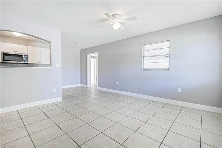 Unfurnished living room featuring a wealth of natural light, ceiling fan, and light tile floors