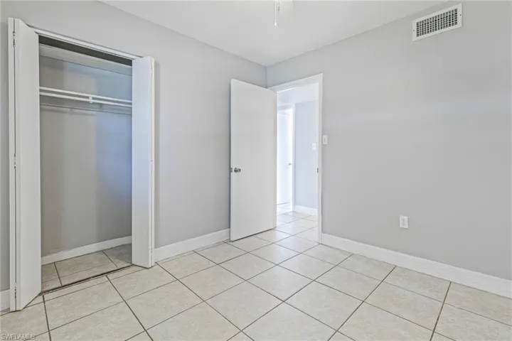 Unfurnished bedroom with a closet and light tile flooring