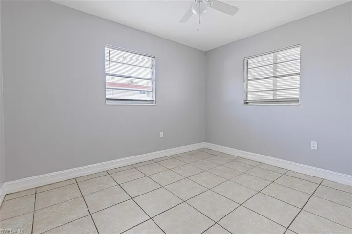 Tiled spare room featuring ceiling fan