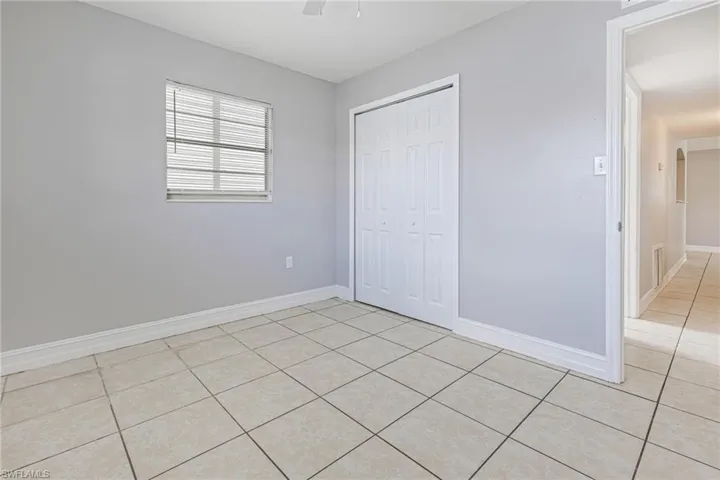 Unfurnished bedroom featuring ceiling fan, a closet, and light tile floors
