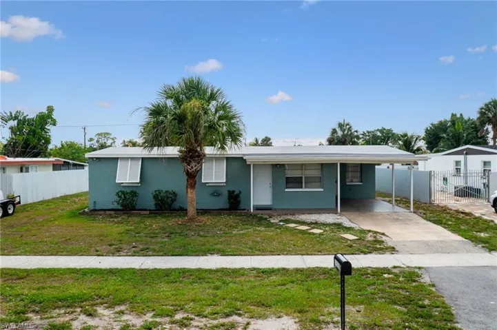 View of front of home with a front yard and a carport