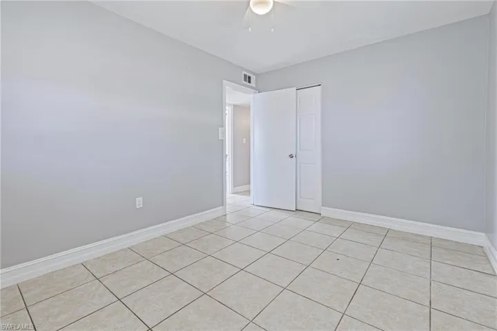 Tiled spare room featuring ceiling fan
