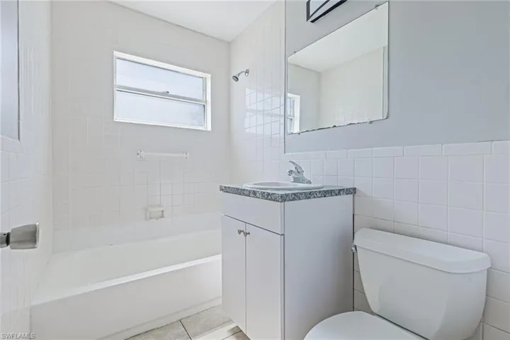 Full bathroom with tile walls, tile floors, and toilet