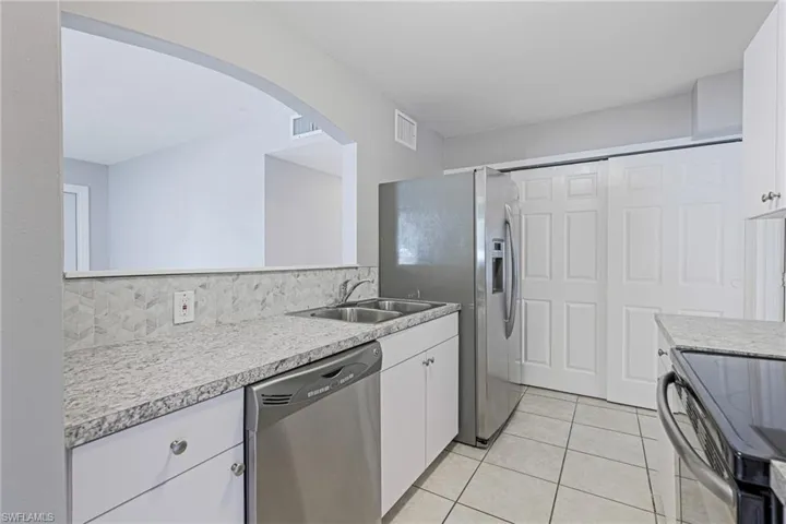 Kitchen featuring tasteful backsplash, dishwasher, light tile floors, sink, and white cabinets